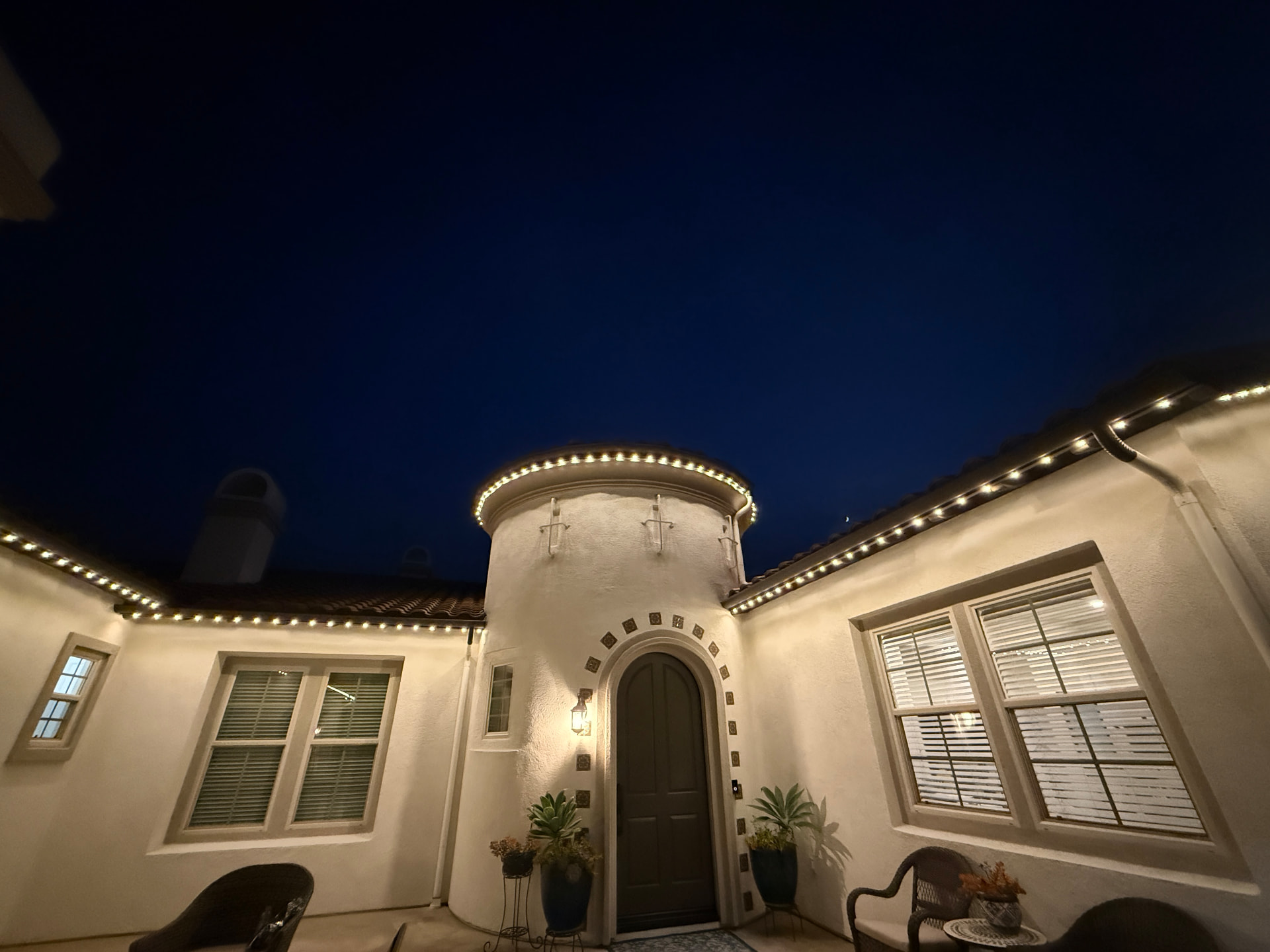 Warm roofline lighting wrapping a turret and courtyard entry
