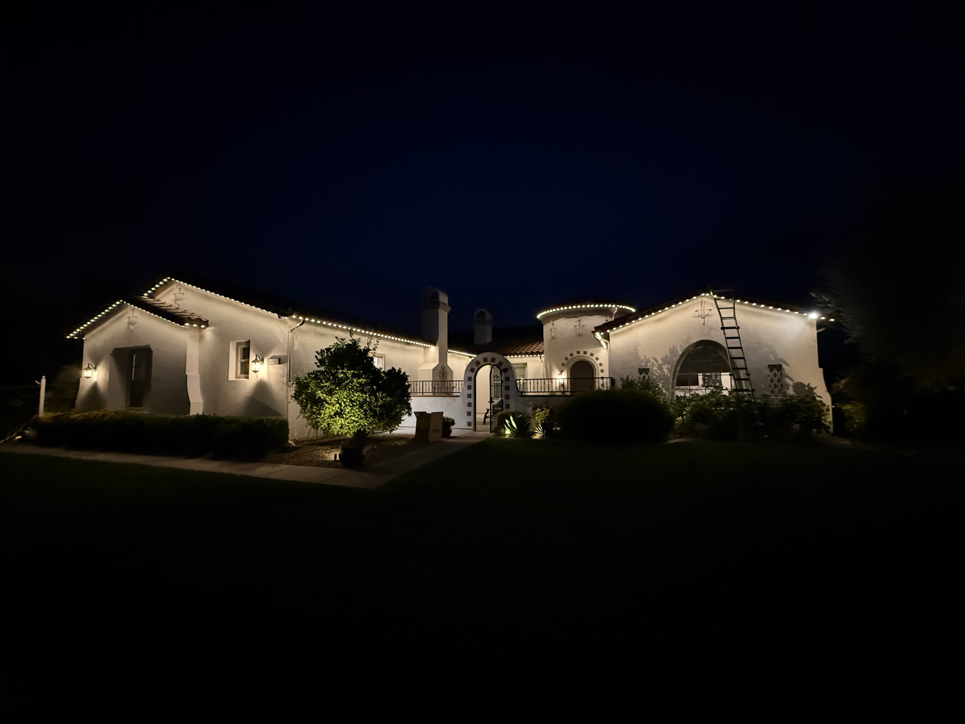 Warm white roofline lighting across a Spanish-style estate at dusk