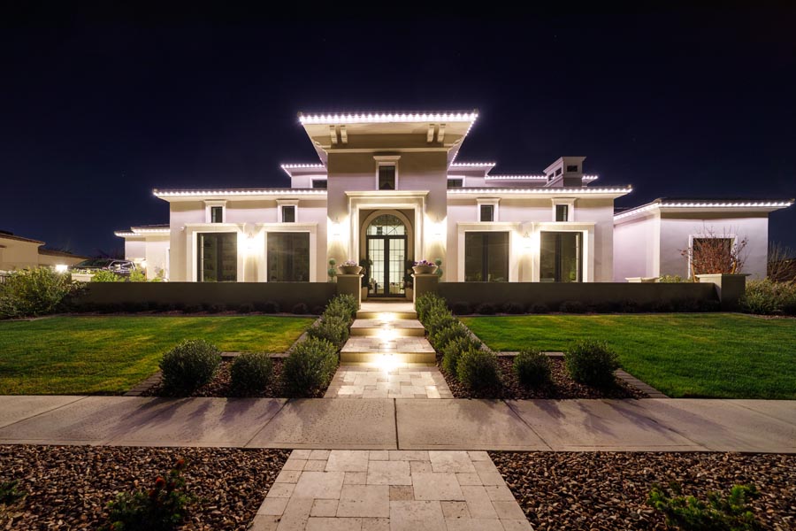 Warm white permanent lighting outlining a modern luxury estate with lit walkway
