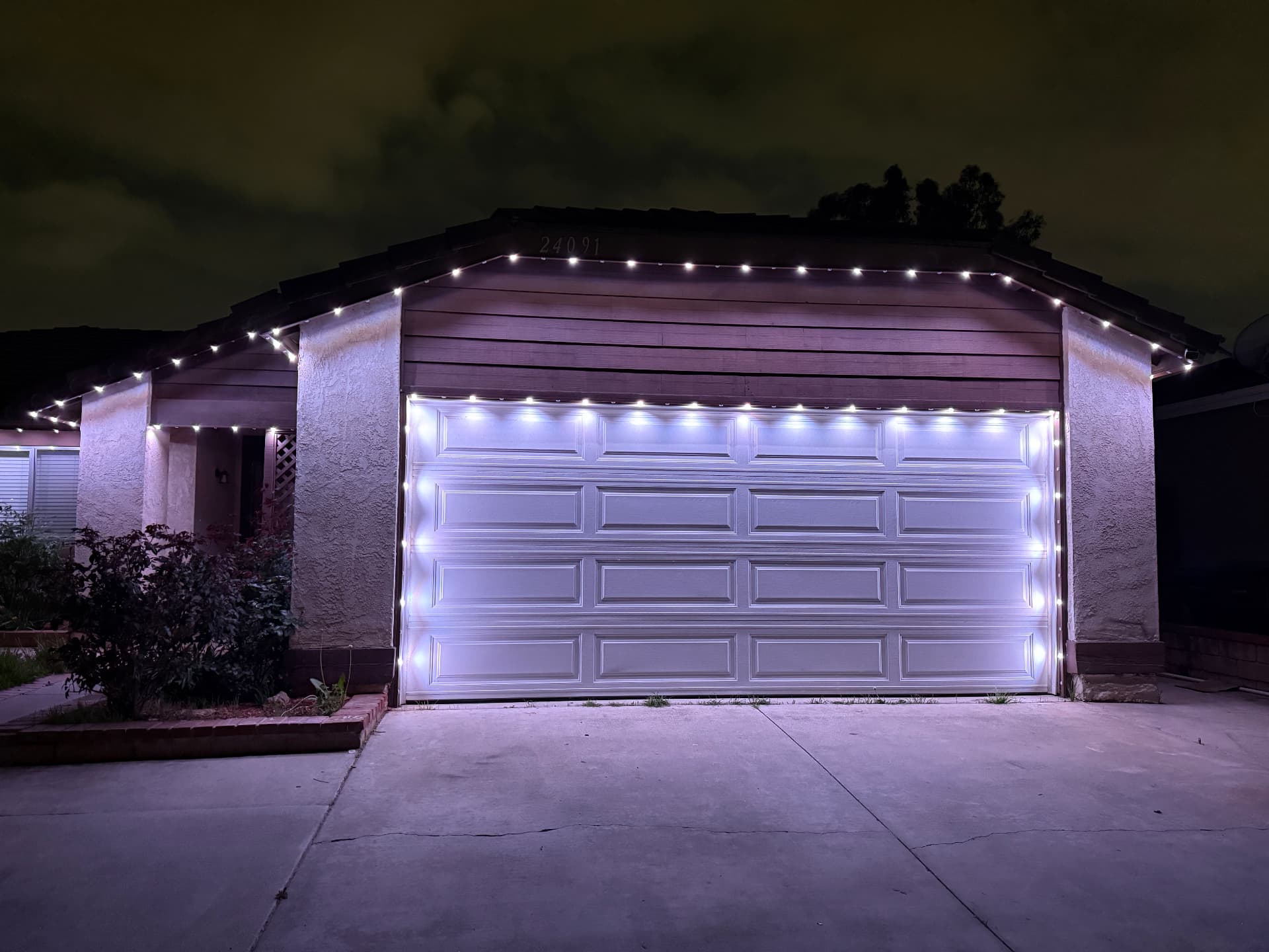 Cool white permanent lighting around a garage and roofline