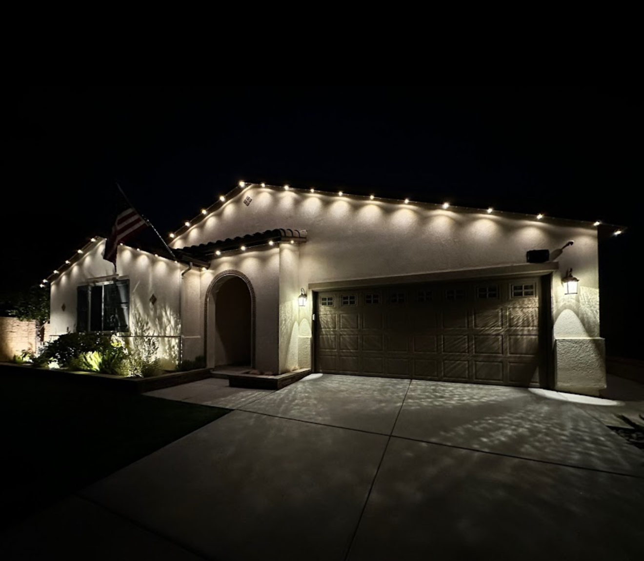 Warm white roofline lighting on a Spanish-style ranch home